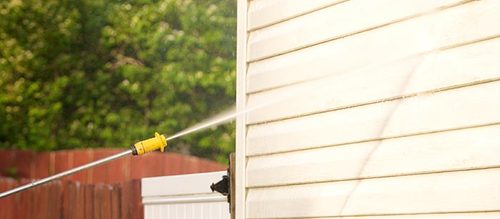 Someone pressure washing exterior of house