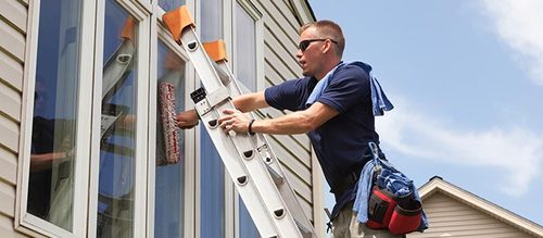 The Squeaky Clean Company employee working on residential window cleaning